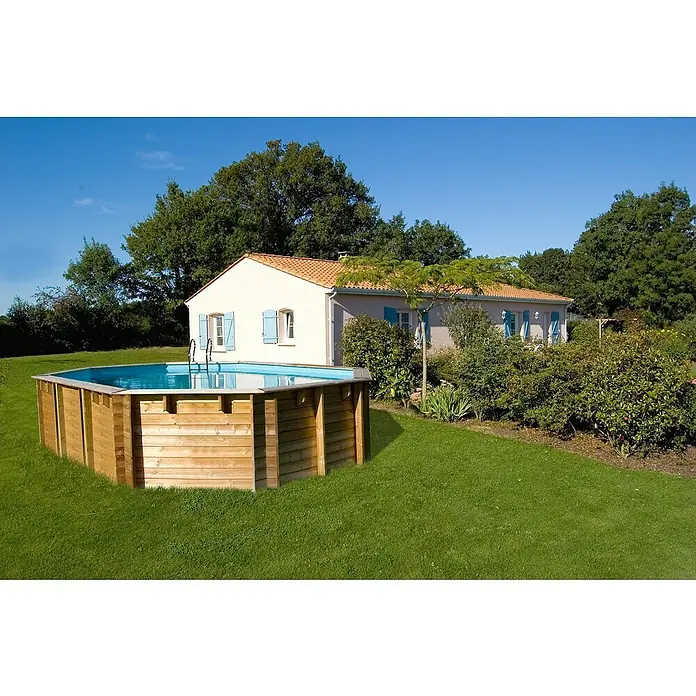 Gre Holz-Pool Vermela - L x B x H: 672 x 472 x 146 cm, Hellbraun, 24.100 l - Ein rechteckiger Holzpool im Garten vor einem Haus mit blauem Fensterladen, umgeben von Rasen und Bäumen.