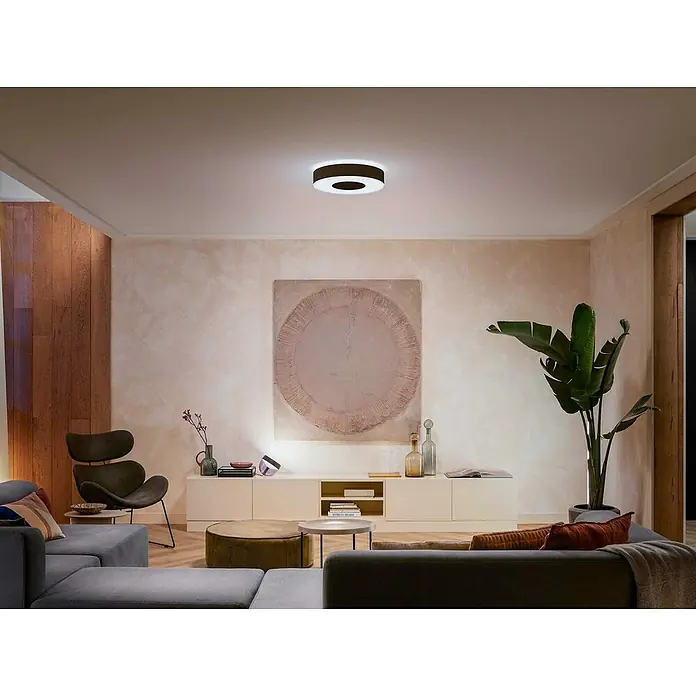 Philips Hue LED-Deckenleuchte rund White and color ambience Infuse M - Ø x H: 38,1 x 8,4 cm, RGBW - Das Bild zeigt eine moderne Deckenleuchte mit einem ringförmigen Design in einem stilvollen Wohnzimmer mit zeitgenössischer Einrichtung.