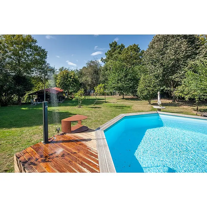 Gre Ducha solar Esencial Deluxe - Altura: 223 cm, Aluminio, Antracita - Vista de un jardín con piscina, terraza de madera y ducha. La piscina invita a nadar, mientras que la ducha está lista para refrescarse.