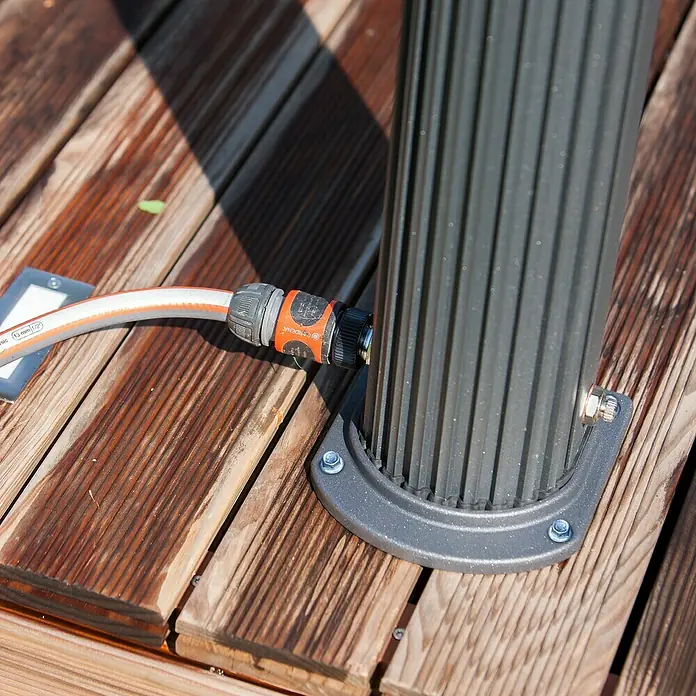 Gre Ducha solar Esencial Deluxe - Altura: 223 cm, Aluminio, Antracita - Primer plano de una manguera de agua de jardín conectada a un pilar de metal, con una cubierta de madera al fondo.