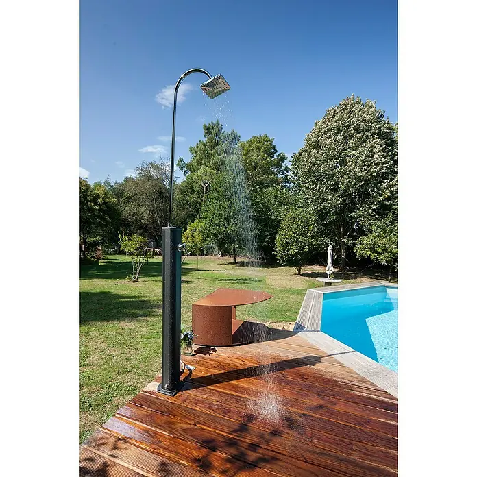 Gre Ducha solar Esencial Deluxe - Altura: 223 cm, Aluminio, Antracita - Ducha exterior con accesorios cromados y poste negro junto a la piscina sobre una cubierta de madera. La ducha está funcionando, regando la madera.