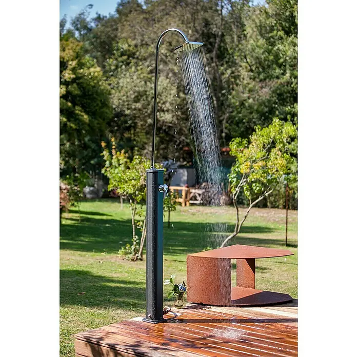Gre Ducha solar Esencial Deluxe - Altura: 223 cm, Aluminio, Antracita - Una ducha exterior moderna con estructura de metal negro y accesorios cromados en una plataforma de madera, rodeada de vegetación.