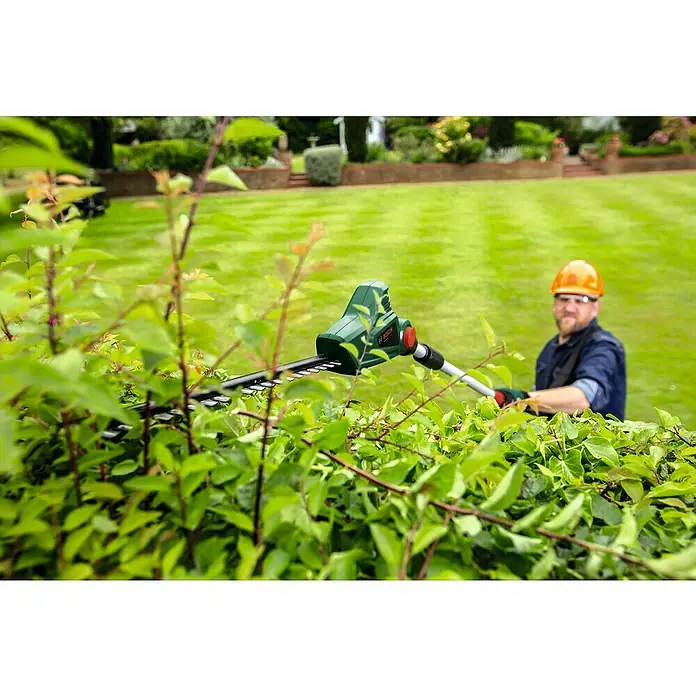 Bosch Power for All 18V Teleskop-Heckenschere UniversalHedgePole 18 - 18 V, Li-Ionen, Ohne Akku, Schnittlänge: 43 cm - Ein Mann benutzt eine Bosch Heckenschere, um eine Hecke zu trimmen. Die Heckenschere ist im Fokus, der Mann im Hintergrund trägt einen Helm.