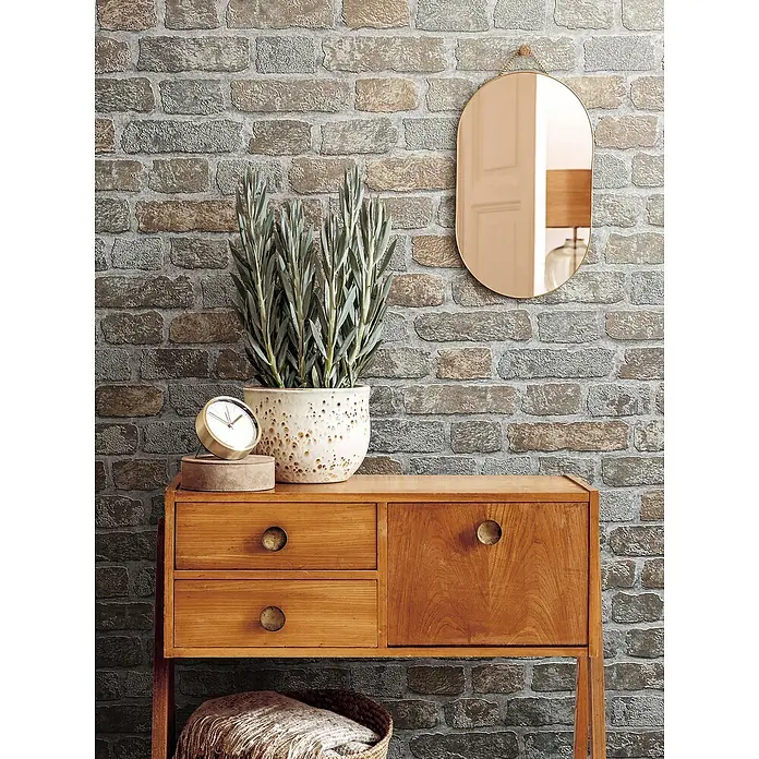 Marburg Sand & Stones Vliestapete Steinmauer II - Graubeige, Steinoptik, 10,05 x 0,53 m - Holzkommode mit Topfpflanze und Spiegel, perfekt für eine stilvolle Inneneinrichtung. Die Kommode bietet Stauraum und dient als dekoratives Element.