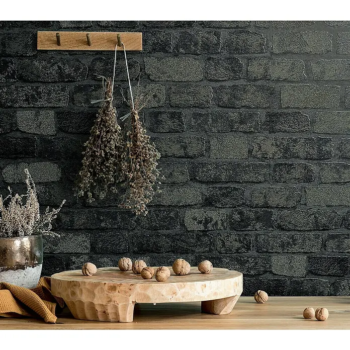 Marburg Sand & Stones Vliestapete Steinmauer I - Grau/Dunkelgrau, Steinoptik, 10,05 x 0,53 m - Rustikale Küchendekoration mit Holzhocker, Walnüssen und Trockenblumen vor einer Backsteinmauer.