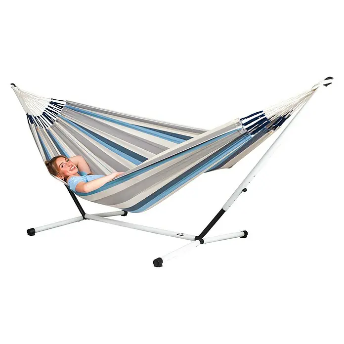La Siesta Hängemattengestell Nautico Double Size - L x B x H: 365 x 115 x 130 cm, Stahl - Entspannte Frau in einer gestreiften Hängematte mit weißem Gestell. Die Hängematte bietet Komfort und Stil für den Garten.