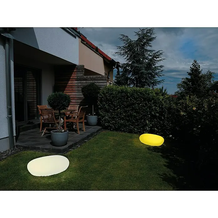 LED-SolarsteinWeiß, L x B x H: 30 x 40 x 16 cm - Eine nächtliche Gartenszene mit zwei Bodenleuchten, die ein weiches Licht auf den Rasen werfen und eine entspannende Atmosphäre schaffen.