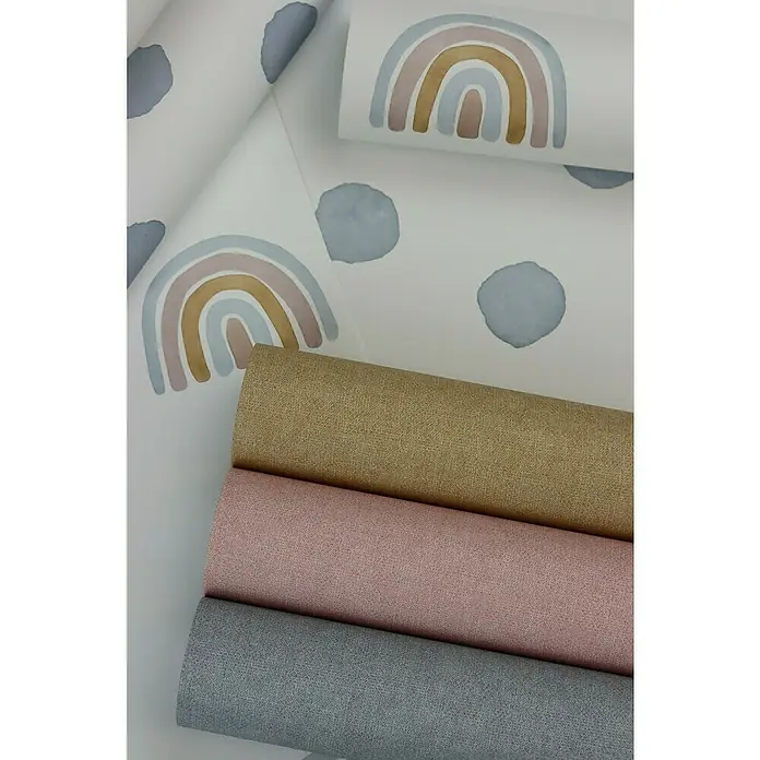 Rasch Bambino XIX Vliestapete Punkte - Blau, Grafisch, 10,05 x 0,53 m - Nahaufnahme von Rollen mit strukturierten Stoffen in Gold-, Rosa- und Grautönen neben Tapeten mit Aquarell-Regenbögen und -Punkten.