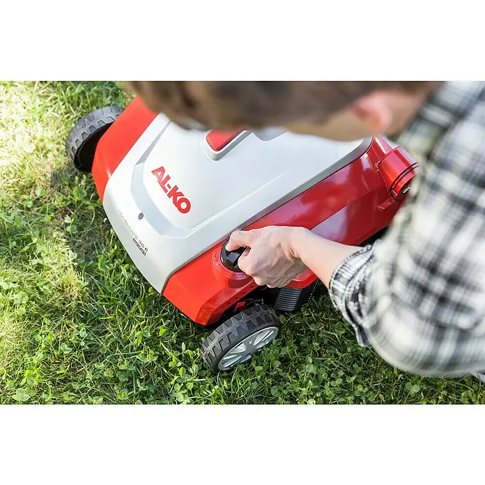 AL-KO Elektro-Vertikutierer-Lüfter Combi Care 36 E Comfort - 1.500 W, Arbeitsbreite: 36 cm - Nahaufnahme eines Mannes, der die Einstellungen an einem AL-KO Kombi-Care 36 E Vertikutierer auf einem Rasen anpasst.
