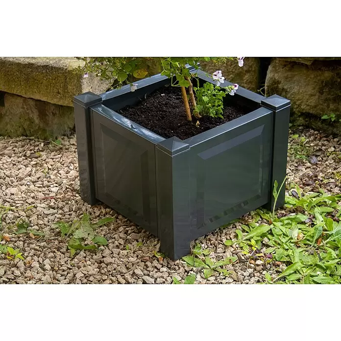 KHW Pflanzkasten - Außenmaß (L x B x H): 43 x 43 x 41 cm, Kunststoff, Anthrazit - Dunkelgrauer quadratischer Pflanzkübel mit Zierpaneelen und spitzen Kappen, gefüllt mit Erde und einer Pflanze, draußen auf Kies.