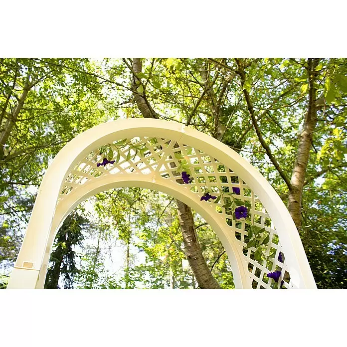 KHW Rosenbogen - Weiß, 174 x 43 x 207 cm, Ausstattung: 2 Pflanzkästen - Weißer Gartenbogen mit Rankgitter, verziert mit lila Blumen und grünen Blättern, im Grünen aufgestellt.