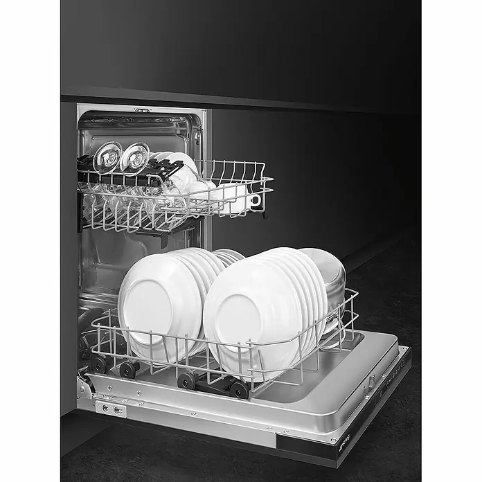 Smeg Lavavajillas integrable ST4512IN - Ancho: 44,6 cm, Número de cubiertos: 9 ud. - Un lavavajillas abierto con vajilla. Los platos y vasos limpios están ordenados en las cestas de alambre del lavavajillas.