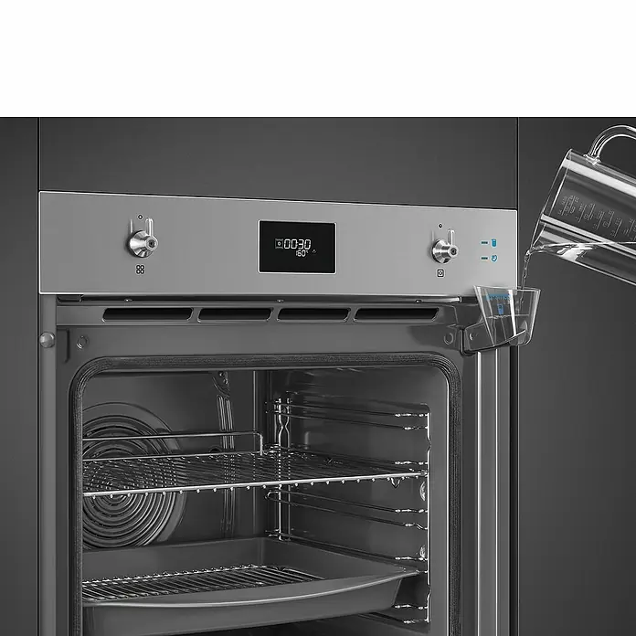 Smeg Horno empotrado SOP6301S2X - Número de tipos de calentamiento: 11 ud., Volumen horno: 68 l, Inox - Imagen de un horno Smeg con una persona vertiendo agua en un recipiente designado para ello. El interior del horno está equipado con rejillas y una bandeja.