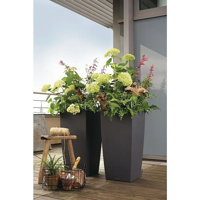 Lechuza Color Pflanzsäule eckig Cubico - Außenmaß (L x B x H): 40 x 40 x 75 cm, Kunststoff, Schiefergrau - Zwei moderne, anthrazitfarbene Pflanzgefäße von Lechuza, bepflanzt mit üppigen Hortensien, Farnen und Salbei, auf einer hölzernen Terrasse.