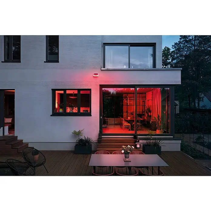 Bosch Smart Home Außensirene - 100 dB - Moderne Hausfassade mit roten Lichteffekten, die eine warme und einladende Atmosphäre schaffen.