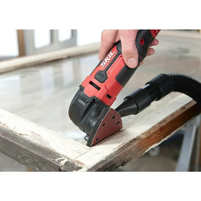 Skil Elektro-Multifunktionswerkzeug 1491 DB - 300 W - Der SKIL Multischleifer wird an einem Fensterrahmen benutzt, um alte Farbreste zu entfernen. Präzision und Effizienz vereint in einem Werkzeug.