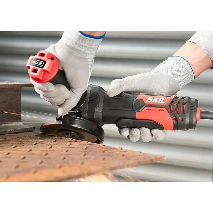 Skil Elektro-Winkelschleifer 9132 AB - 850 W, Durchmesser Scheibe: 125 mm, Leerlaufdrehzahl: 12.000 U/min - Nahaufnahme eines SKIL Winkelschleifers bei der Arbeit an Metall, getragen mit Arbeitshandschuhen.