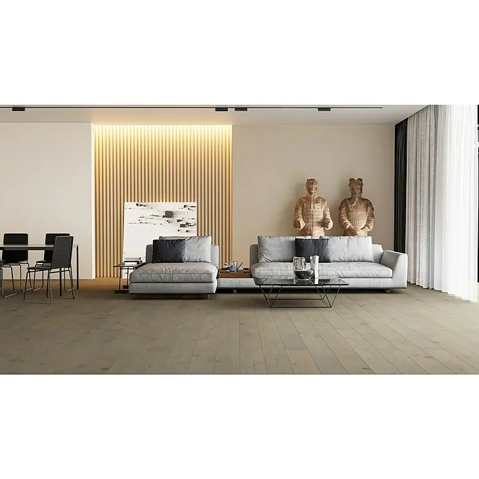 Rodapié roble gris tierra - 2,4 m x 70 mm x 15 mm - Un elegante salón con pisos de madera clara, sofás grises y elementos decorativos como estatuas y obras de arte, una combinación perfecta de estilo y confort.