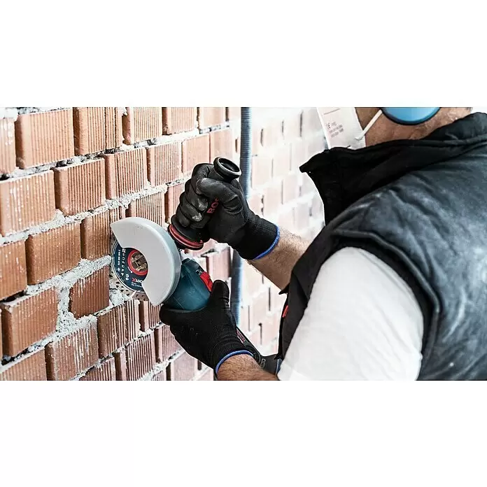 Bosch Professional X-Lock Diamant-Trennscheibe Expert for MultiMaterial - Durchmesser Scheibe: 125 mm - Akku-Winkelschleifer mit Trennscheibe wird zum Schneiden einer roten Ziegelwand verwendet.