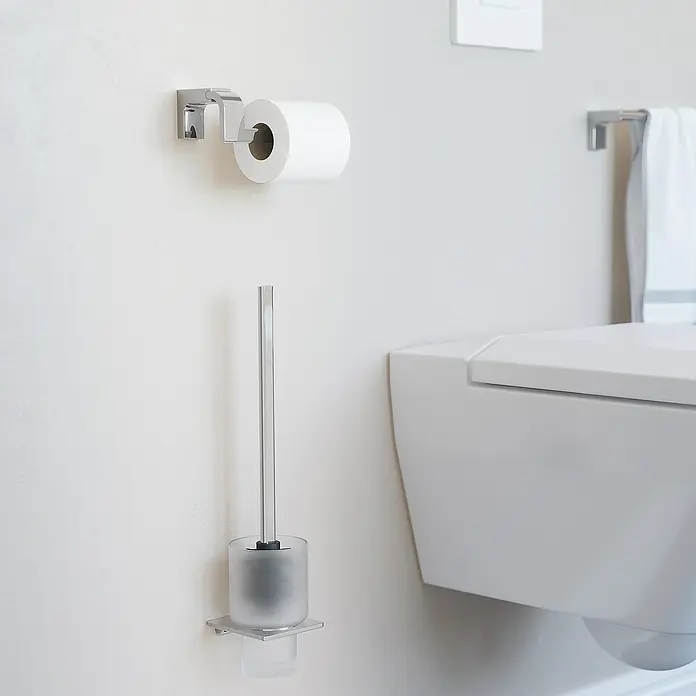 Creabath Elegance Portarrollos papel higiénico - Sin tapa, Cromo - Un baño con un portarrollos, un escobillero y un inodoro. La escena es limpia y de diseño minimalista.