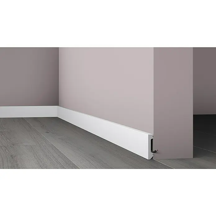 Nmc Decoflair Moldura de poliestireno decorativa M58 - 2 m x 1,3 cm x 5,8 cm, Polímero extruido de alta densidad (HDPS) - Primer plano de un rodapié blanco fijado a una pared con canalización de cables, que muestra una estética limpia y moderna.