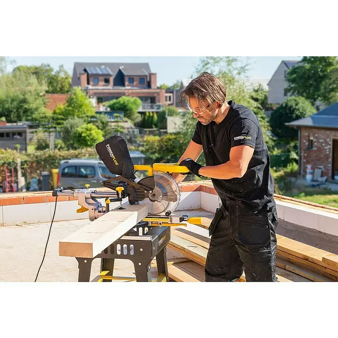 PowerPlus Sierra ingletadora POWX075720DB - 1.600 W, Diámetro hoja de sierra: 210 mm, Número de revoluciones de marcha en vacío: 5.000 r.p.m. - Un hombre usa una sierra de inglete POWERPLUS para cortar un trozo de madera al aire libre, destacando la precisión y potencia de la herramienta.