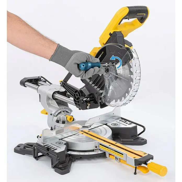 PowerPlus Sierra ingletadora POWX075720DB - 1.600 W, Diámetro hoja de sierra: 210 mm, Número de revoluciones de marcha en vacío: 5.000 r.p.m. - Una sierra ingletadora amarilla y negra en acción, con una mano usando un destornillador en la sierra.
