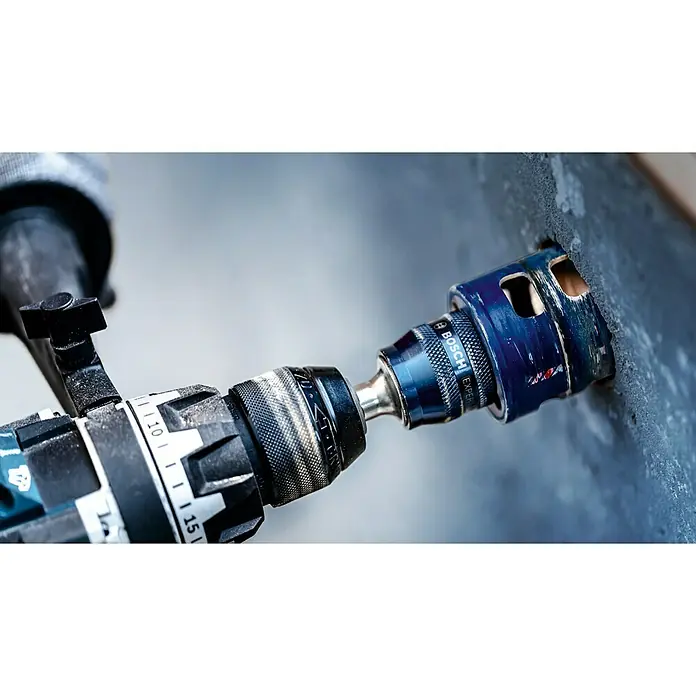 Bosch Expert Bohrmaschinenadapter - Ø x L: 7,15 x 105 mm, 2 -tlg. - Bohrmaschine mit einem Bosch Expert Lochsäge Aufsatz beim Bohren eines Loches in eine graue Oberfläche.