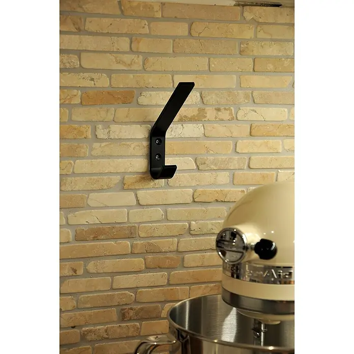 Siro Garderobenhaken - L x B x H: 19 x 120 x 75 mm, Anzahl Haken: 1 Stk., Aluminium - Nahaufnahme eines schwarzen Wandhakens an einer Ziegelwand, daneben eine cremefarbene Küchenmaschine.