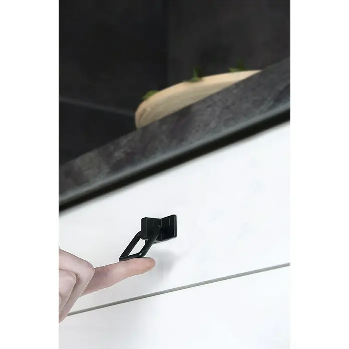 Siro Türklopfer - L x B x H: 51 x 50 x 20 mm, Stahl - Nahaufnahme eines schwarzen Möbelgriffs an einer weißen Schublade mit einem Finger, der ihn berührt. Elegantes und modernes Design.