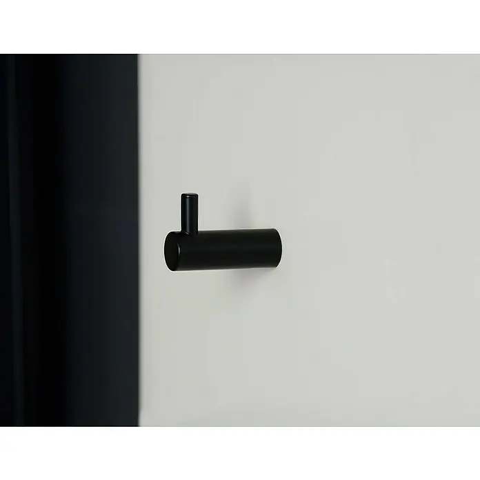 Siro Garderobenhaken - L x B x H: 40 x 14 x 28 mm, Schwarz - Nahaufnahme eines schwarzen, modernen Wandhakens an einer weißen Wand mit angedeuteter schwarzer Fläche links.