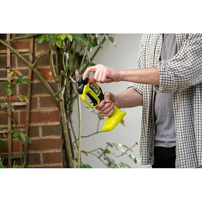 Ryobi ONE+ Maschinenpaket - Akku-Gartenschere RY18SCXA-0,18V, 4 Ah Akku & 2A Ladegerät - Nahaufnahme einer Ryobi Akku-Gartenschere beim Beschneiden einer Pflanze.