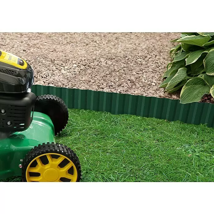 Gardol Rasenkante - Grün, 9 m x 20 cm - Grüner gewellter Rasenbord trennt Rasen von Kiesweg, mit Teilaussicht auf Rasenmäher und Pflanzen.