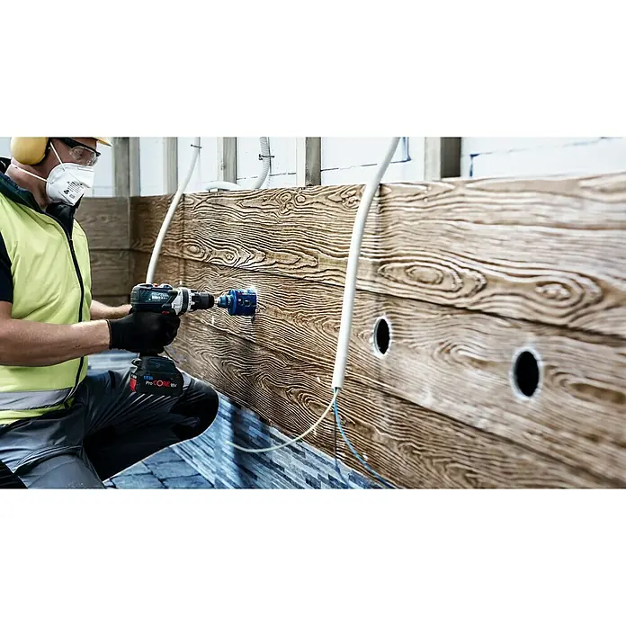 Bosch Professional Expert Bohrkrone Tough Material - Durchmesser Bohrer: 68 mm, 1 Stk. - Ein Handwerker bohrt mit einer Bosch Akku-Bohrmaschine ein Loch in eine Holzstruktur. Die Maschine ist mit einem blauen Bohraufsatz versehen.