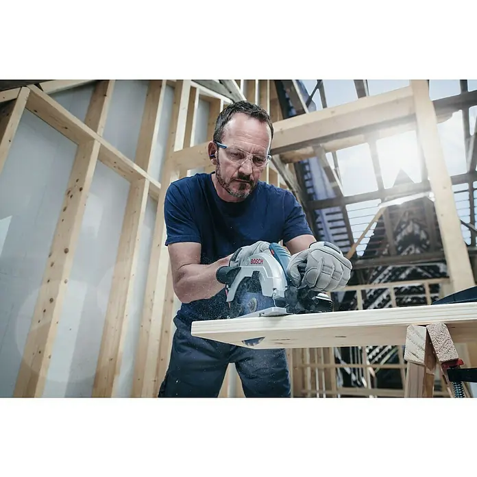 Bosch Kreissägeblatt Expert for Wood - 216 mm, Bohrung: 30 mm, Anzahl Zähne: 48 Stk. - Ein Handwerker in Schutzbrille benutzt eine Bosch Kreissäge, um ein Holzbrett zu schneiden. Sichere und präzise Schnitte sind garantiert.
