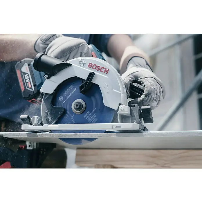 Bosch Expert Kreissägeblatt Expert for Fibre Cement - 165 mm, Bohrung: 15,87 mm - 20 mm, Anzahl Zähne: 4 Stk. - Nahaufnahme einer Bosch Akku-Kreissäge in Aktion, die durch ein Holzbrett schneidet, bedient von einer Person mit Arbeitshandschuhen.