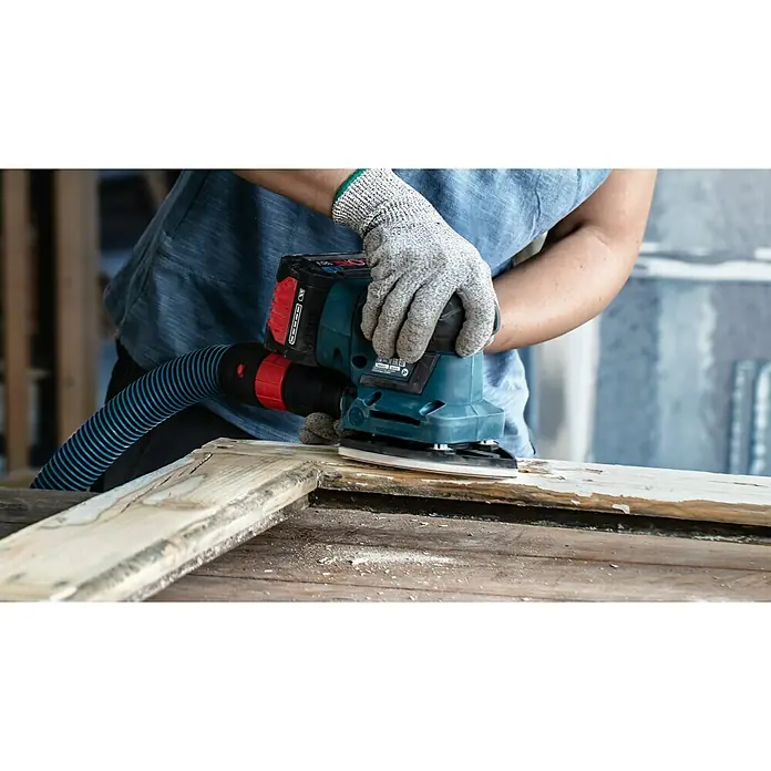 Bosch Expert Schleifpapier C470 - L x B: 115 x 107 mm, Körnung: 60, 10 Stk. - Ein Arbeiter schleift mit einem Bosch Exzenterschleifer ein Holzstück, um es zu bearbeiten und zu glätten, wobei ein Staubsauger angeschlossen ist.