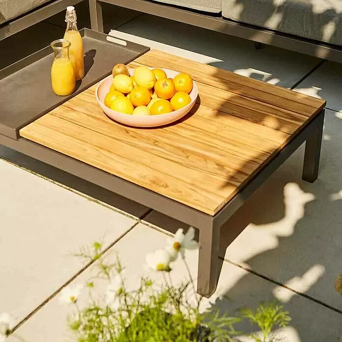 Siena Garden Loungemöbel-Set Alvida - 5 -tlg., Anthrazit/Schwarz, Teakholz, Tablett, Max. Personenzahl: 5 - Grauer Metall-Outdoor-Couchtisch mit Holzplatte und integriertem grauen Tablett, auf einer Terrasse mit Getränken und Obst.