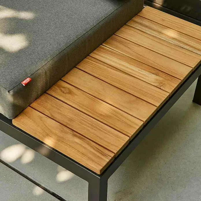 Siena Garden Loungemöbel-Set Alvida - 8 -tlg., Anthrazit/Schwarz, Teakholz, Max. Personenzahl: 6 - Nahaufnahme eines grauen Kissens und einer hölzernen Tischplatte auf einem modernen, dunklen Gestell, ideal für den Außenbereich.