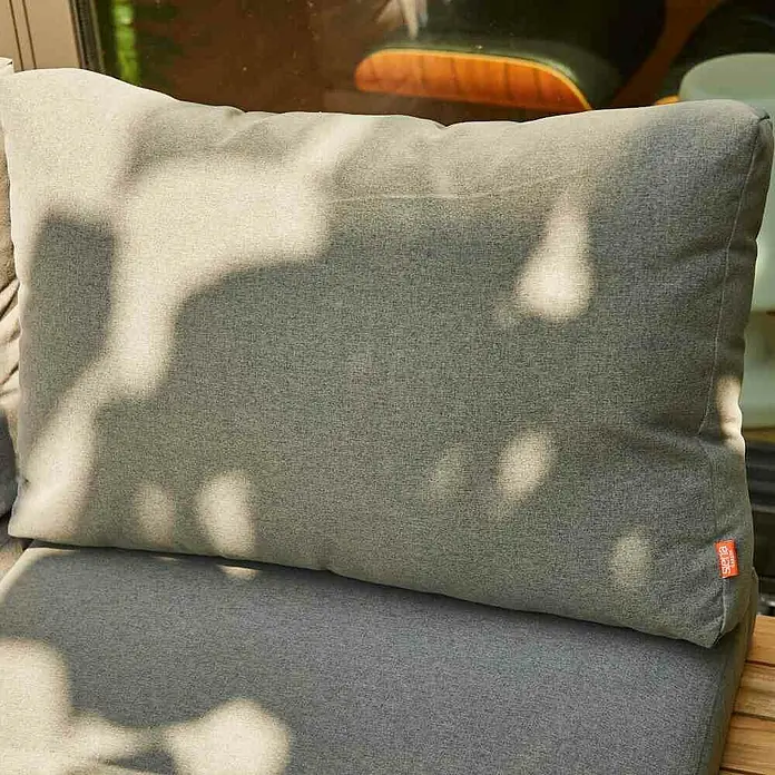 Siena Garden Loungemöbel-Set Alvida - 8 -tlg., Anthrazit/Schwarz, Teakholz, Max. Personenzahl: 6 - Nahaufnahme eines grauen Sofakissens mit einem kleinen Markenetikett in einem gemütlichen Außenbereich.