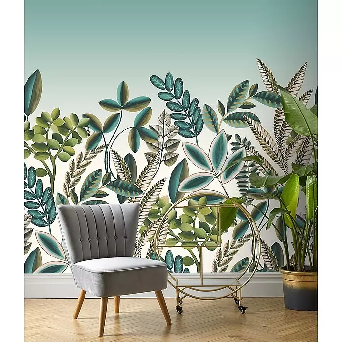 Rasch Florentine III Fototapete Tropischer Garten - B x H: 300 x 300 cm, Vlies, Scandi - Eleganter grauer Samtsessel mit naturfarbenen Holzbeinen, in einem Raum mit botanischer Tapete und einem goldenen Servierwagen, der ein gemütliches Wohnambiente zeigt.