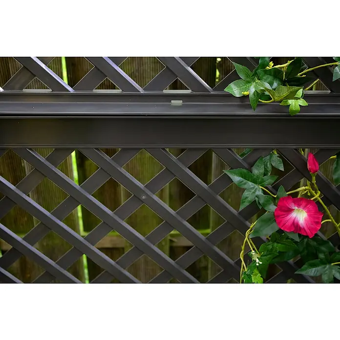 KHW Rankgitter - 100 x 140 cm, Anthrazit - Nahaufnahme eines dunkelbraunen Spalierzauns mit künstlichen Kletterpflanzen und einer pinkfarbenen Blüte, der einen Hauch von Natur verleiht.