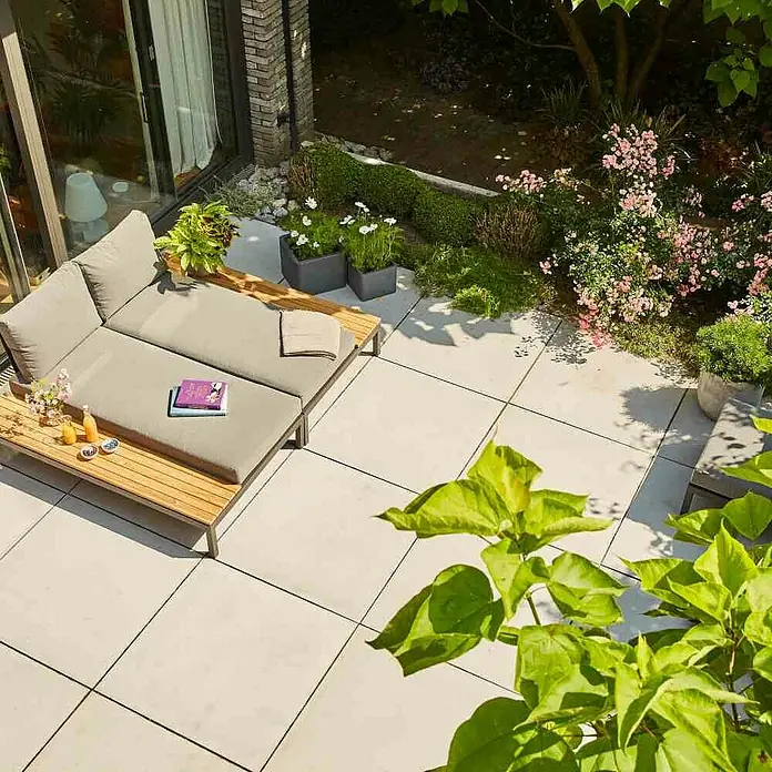 Siena Garden Loungemöbel-Set Alvida - 2 -tlg., Anthrazit/Schwarz, Teakholz, Max. Personenzahl: 2 - Blick auf eine Terrasse mit einem stilvollen Loungesofa, umgeben von üppigem Grün und blühenden Pflanzen. Der perfekte Ort zum Entspannen.