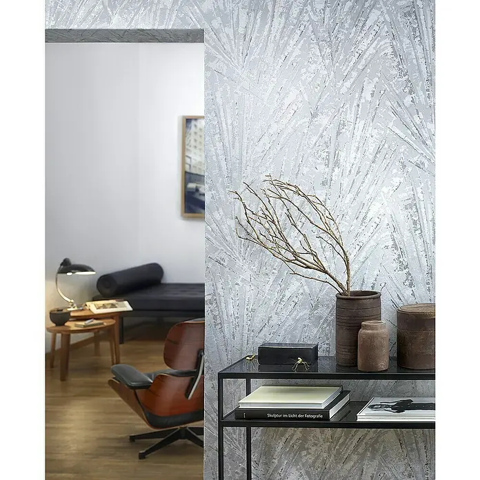Marburg Papis Loveday Vliestapete Allover-Struktur - Grau/Silber, Grafisch, 10,05 x 0,7 m - Ein Interieur mit einer Wand mit einem auffälligen Muster und einem schwarzen Regal, auf dem dekorative Accessoires und Bücher stehen.