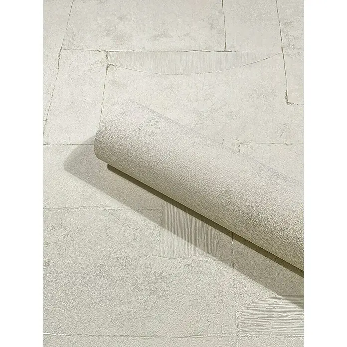Marburg Papis Loveday Vliestapete I - Beigegrau, Grafisch, 10,05 x 0,7 m - Nahaufnahme einer Rolle cremefarbener Vinyltapete mit strukturiertem Steindesign, die auf einem passenden Hintergrund liegt.