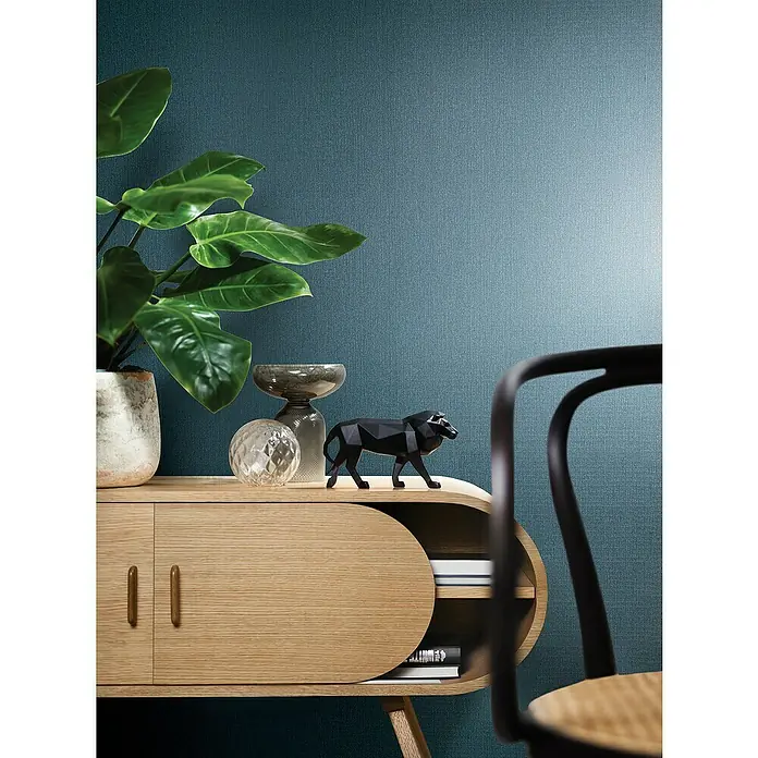Marburg Papis Loveday Vliestapete - Blau/Türkis, Uni, 10,05 x 0,7 m - Elegantes Sideboard aus Eichenholz mit stilvoller Dekoration wie Pflanze, Glaskugel und schwarzer Pantherfigur, ideal für modernes Wohnambiente.