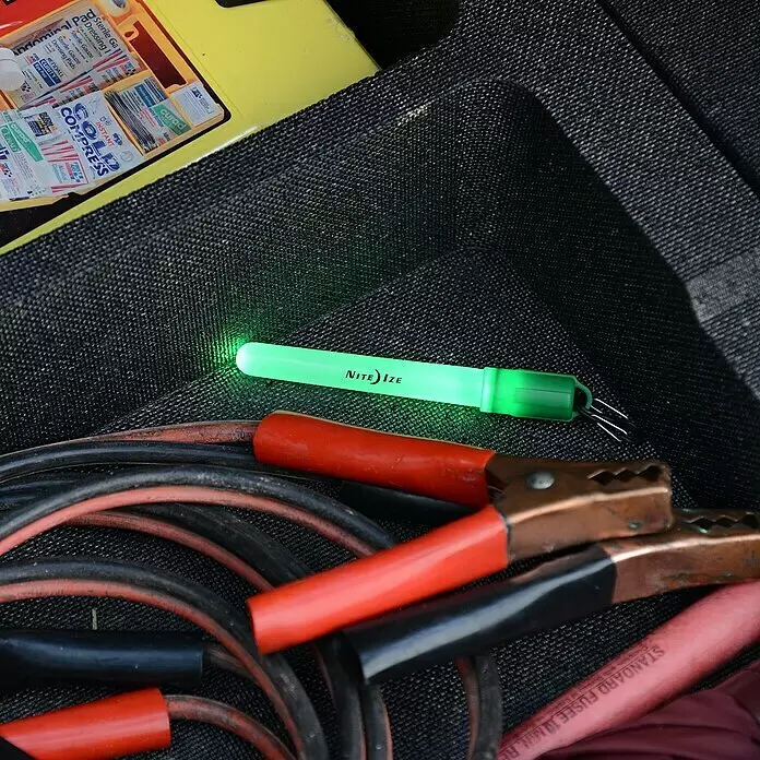 Nite Ize Barra luminosa LED mini - Rojo - Una luz de baliza Nite Ize verde brillante, cables de arranque y un botiquín en el compartimento de almacenamiento del coche.