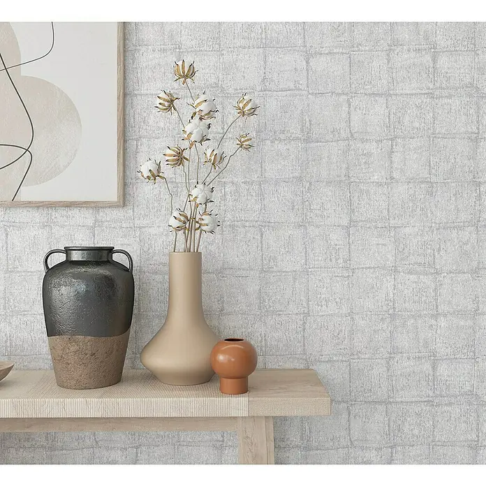 Marburg Botanica Vliestapete - Grau, Fliesenoptik, 10,05 x 0,53 m - Wandbild mit abstrakter Kunst, einer hohen Vase mit Baumwollzweigen und zwei kleineren Vasen, die auf einem hellen Holzregal arrangiert sind.
