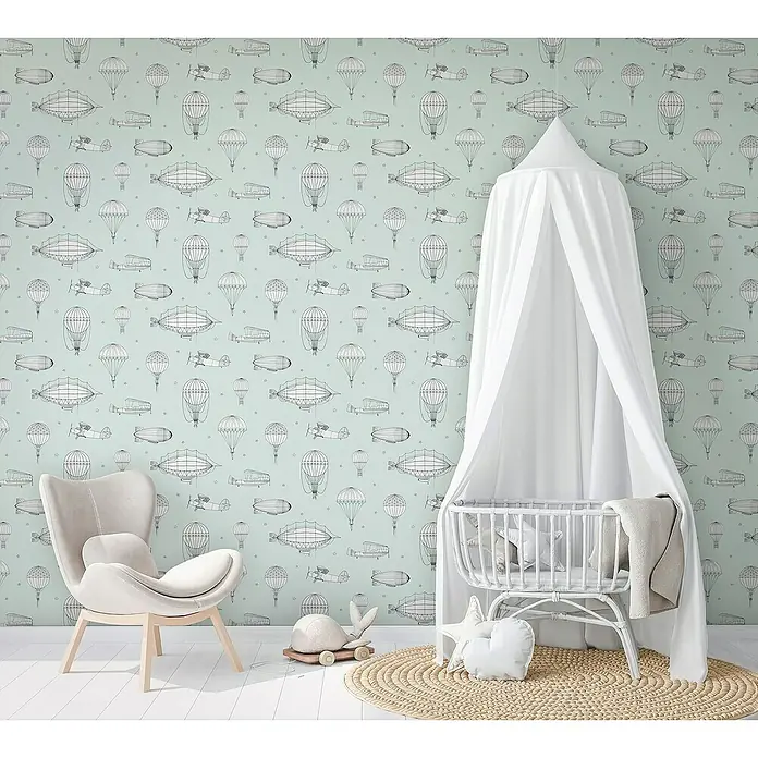 Marburg Kids' Walls Vliestapete Luftschiffe - Grün/Weiß, Grafisch, 10,05 x 0,53 m - Kinderzimmer mit einem mintfarbenen Hintergrund, verziert mit gezeichneten Luftschiffen und Flugzeugen. Ein weißes Kinderbett und ein Sessel ergänzen das Bild.