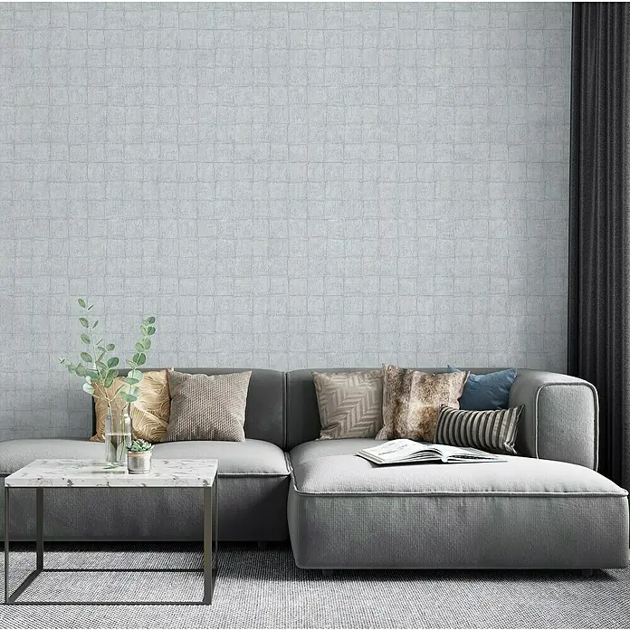 Marburg Botanica Vliestapete - Blau/Grau, Fliesenoptik, 10,05 x 0,53 m - Nahaufnahme eines modernen Wohnzimmers mit einem grauen Sofa, dekorativen Kissen und einem stilvollen Couchtisch.